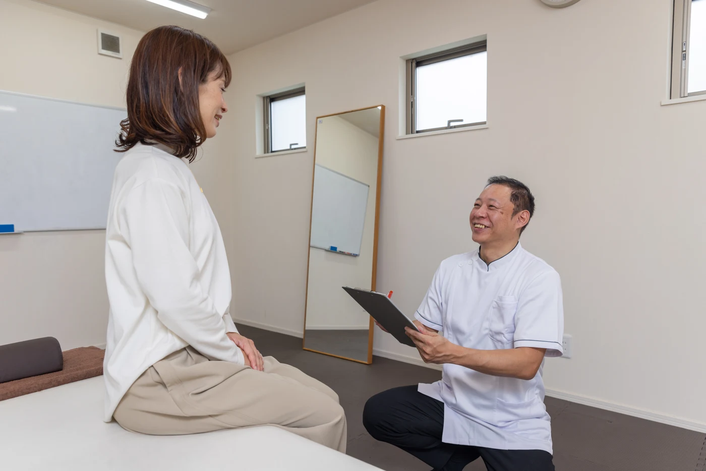 院長が施術前に椅子に座ってお話を伺う様子